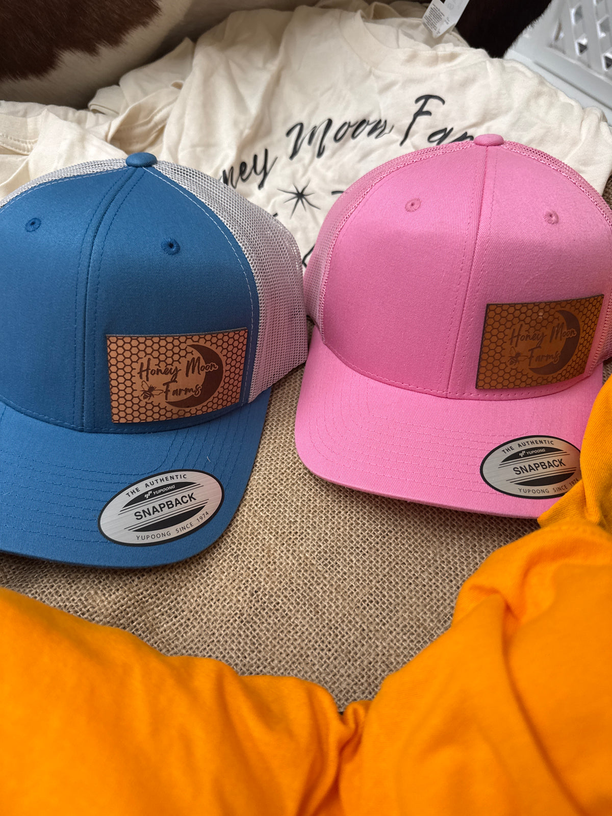 Pink and blue caps with visible brand logos on leather patches with a textured surface.